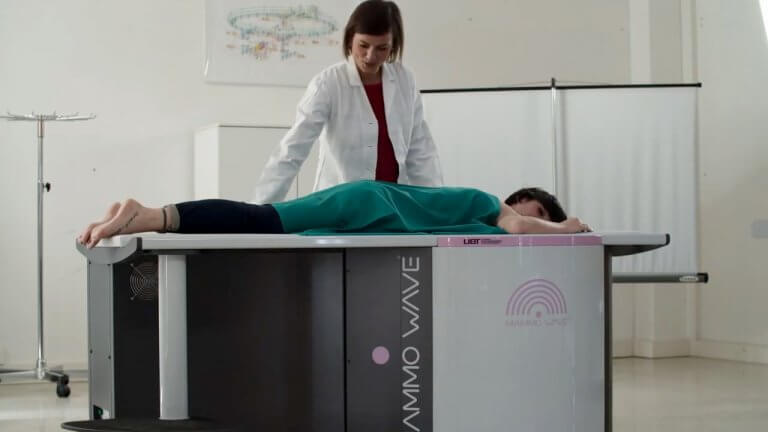 Donna sdraiata su un dispositivo medico con una dottoressa in piedi